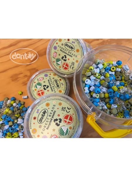 Gennemsigtige beholdere med blå og grønne perler på træbord